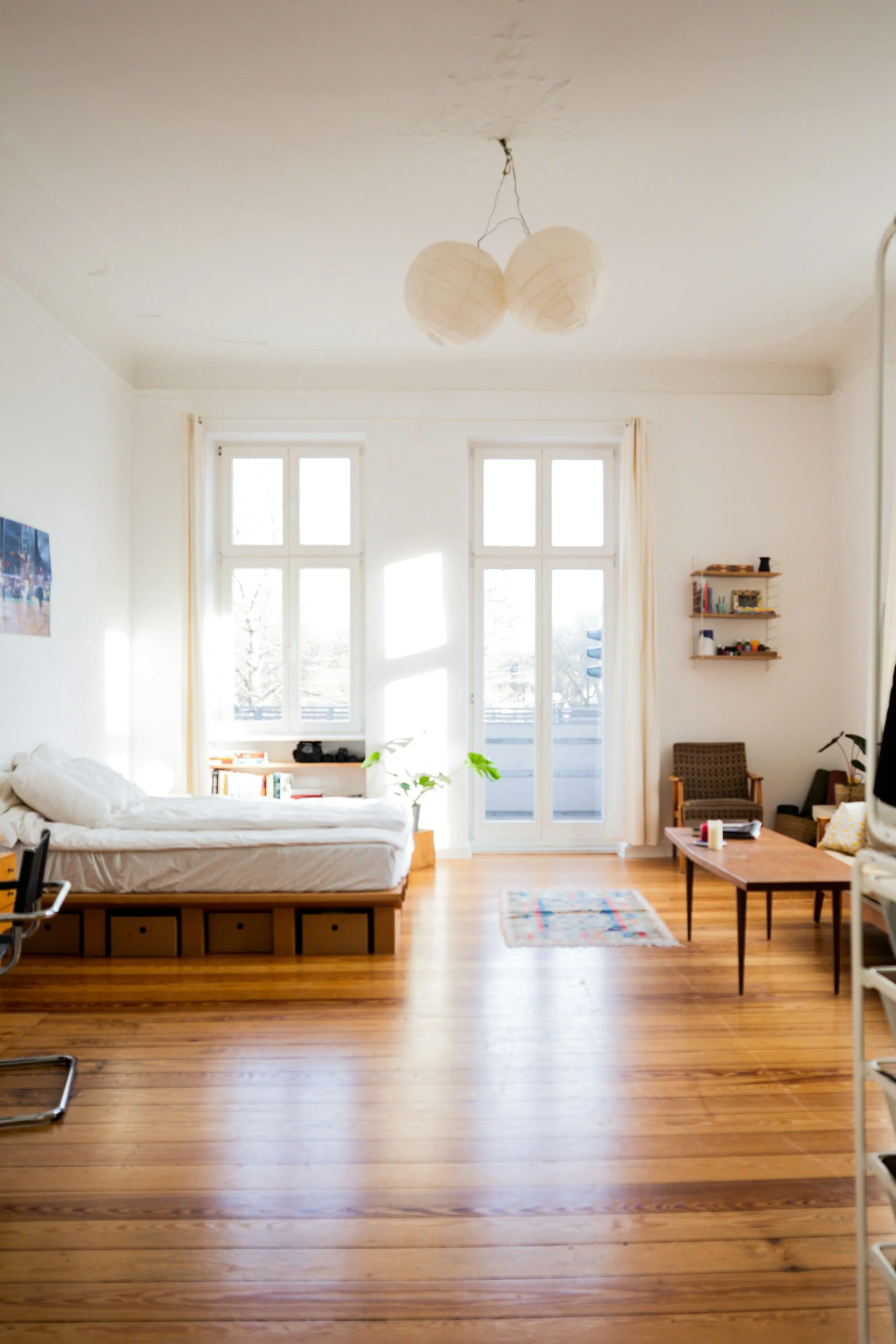 A bright bedroom with a freshly made bed beneath tall sash windows