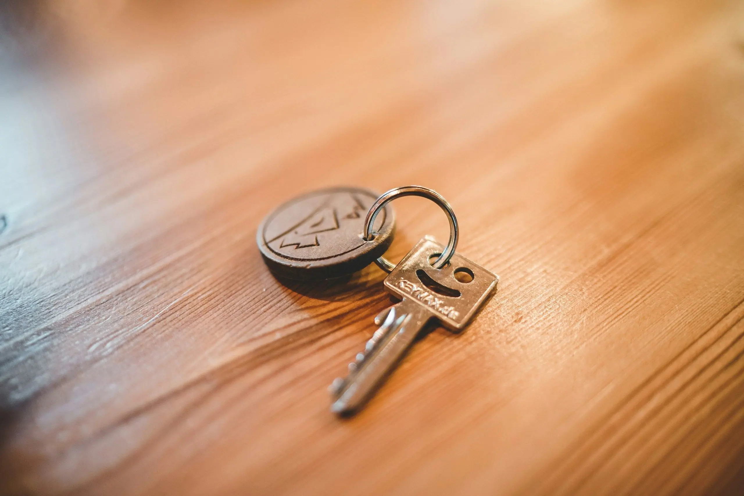 A single key on a key ring resting on a wooden table