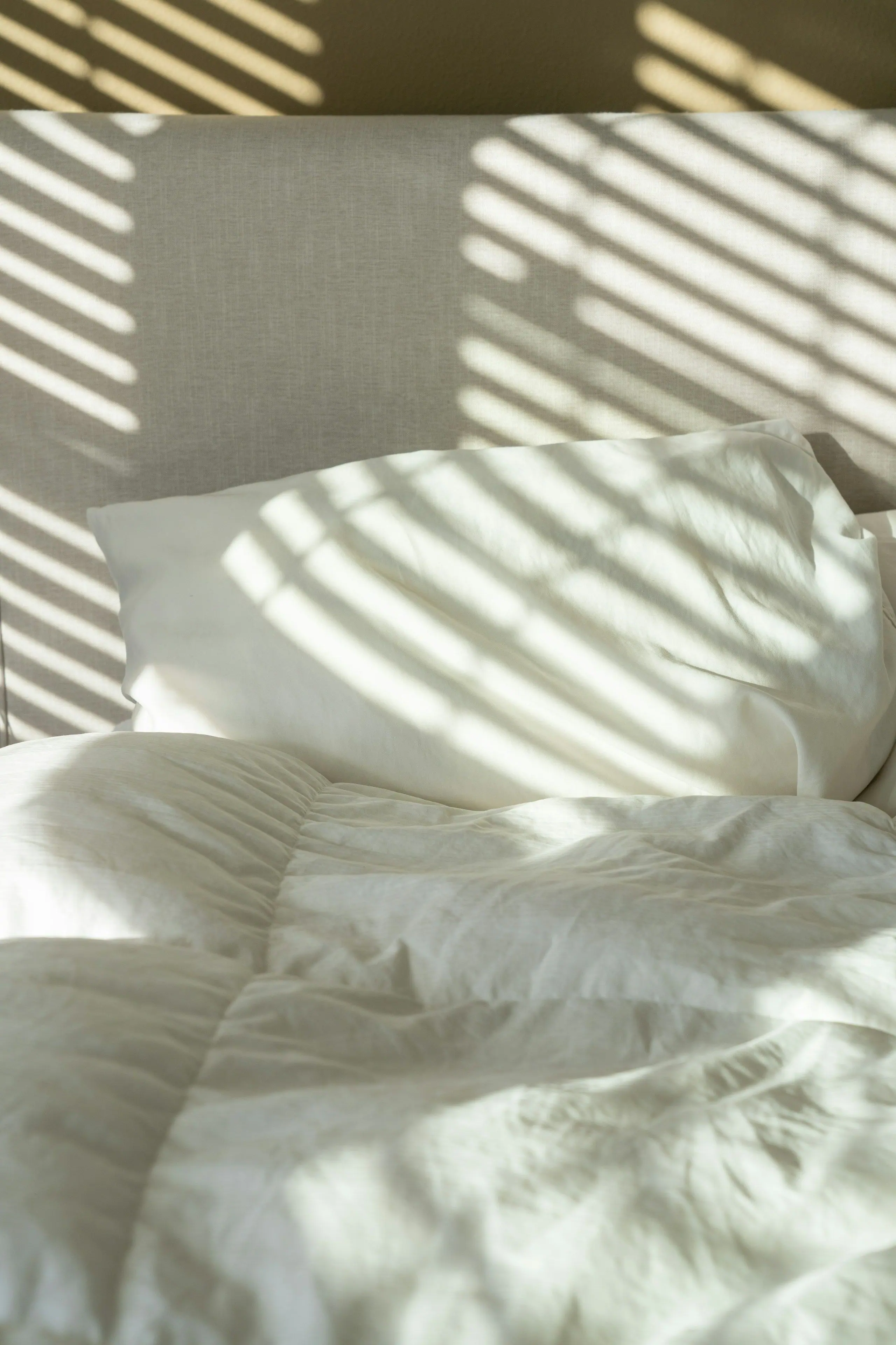 Morning light falling across white pillows and a duvet