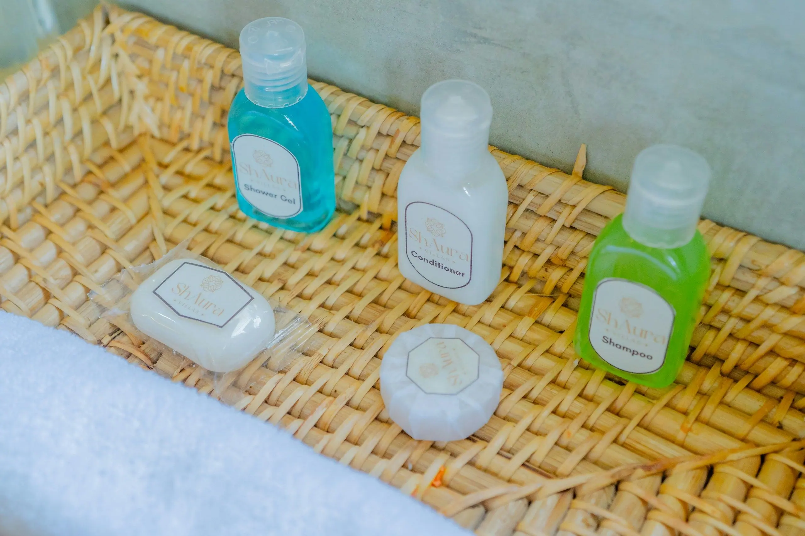 Small bottles of shampoo, conditioner and shower gel neatly arranged in a woven basket