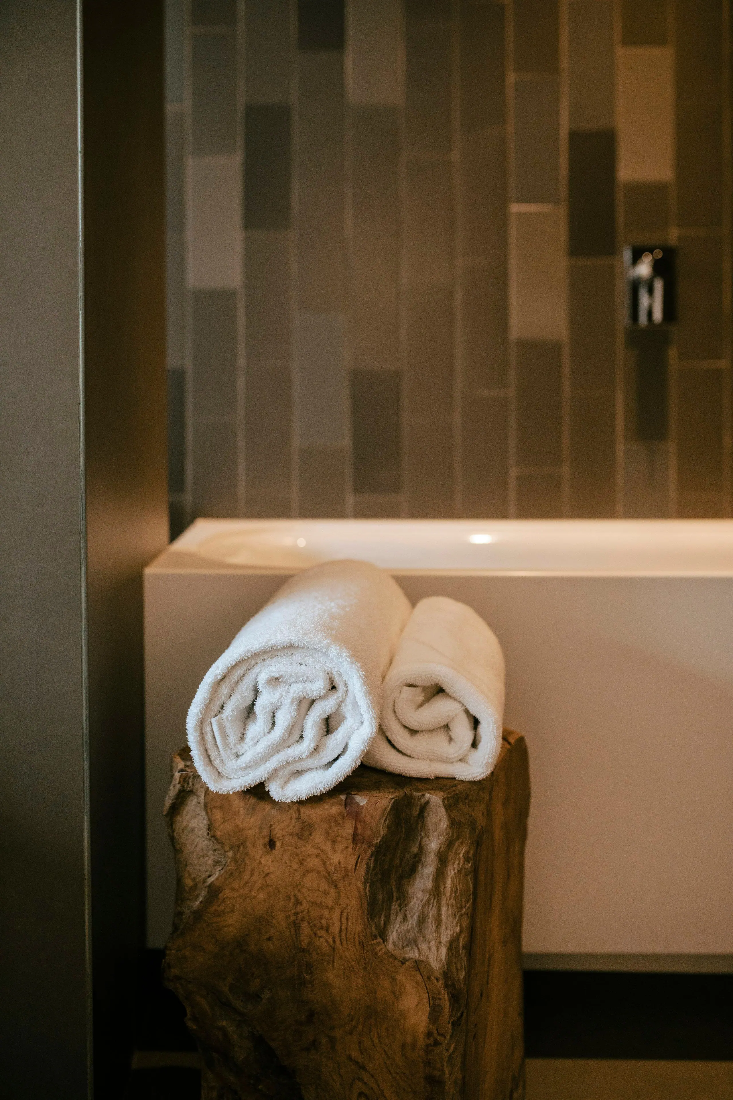 Rolled white towels on the edge of a bath