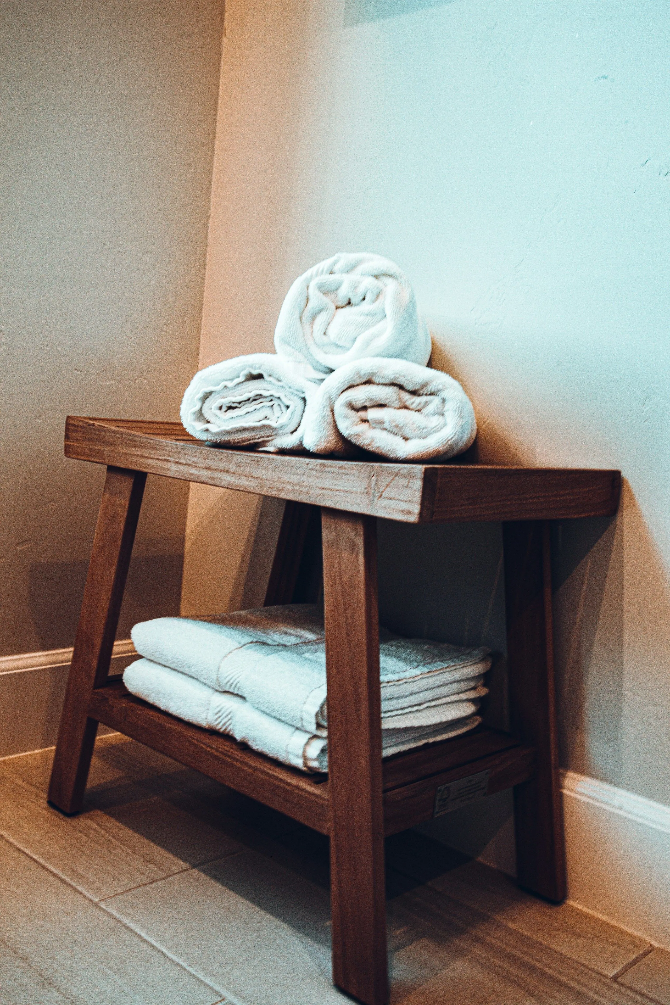 Rolled and folded white towels on a wooden stool